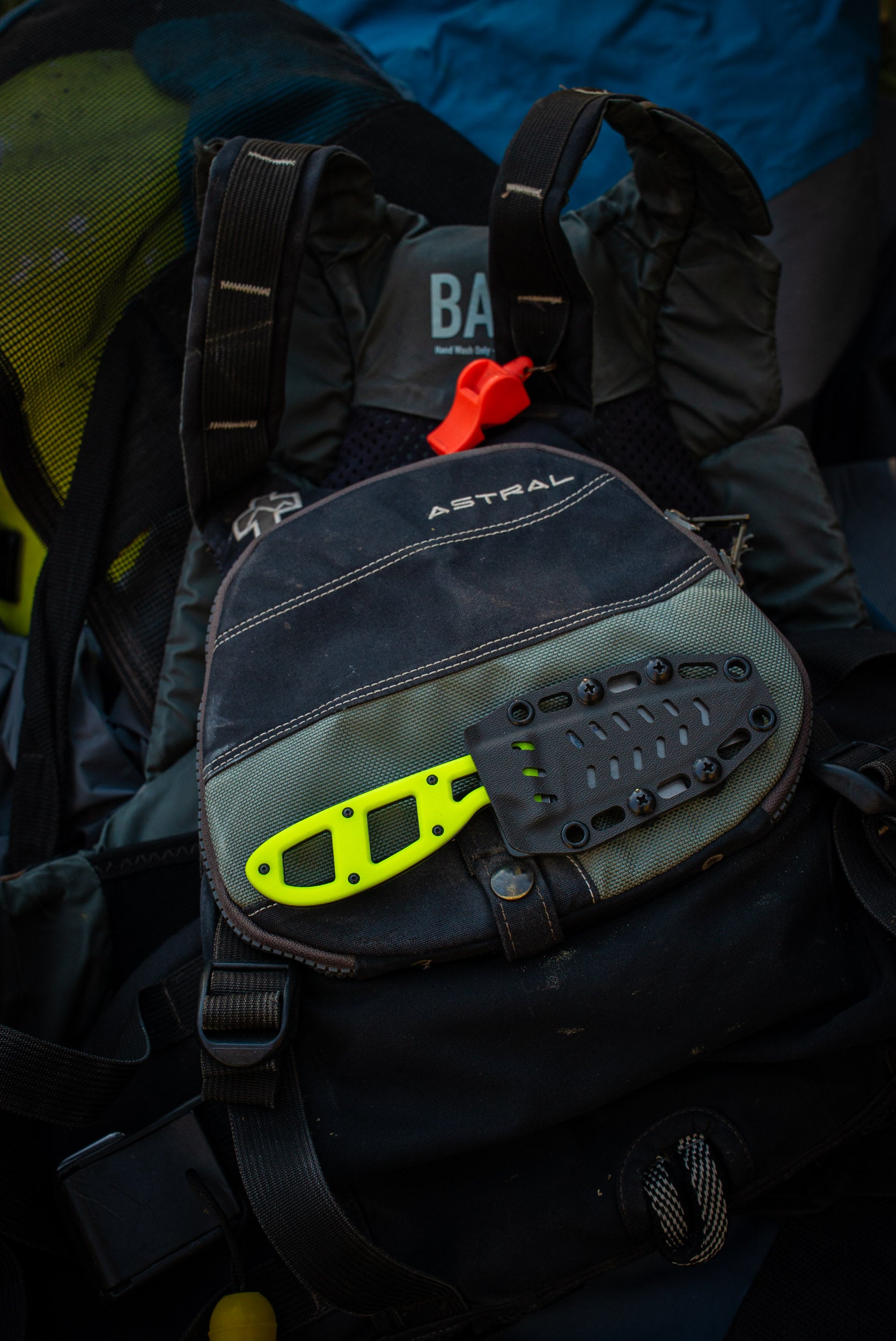 PFD for whitewater kayaking on a dark background with a river knife attached to it